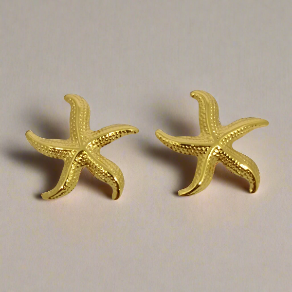 Gold starfish earrings on a light gray background