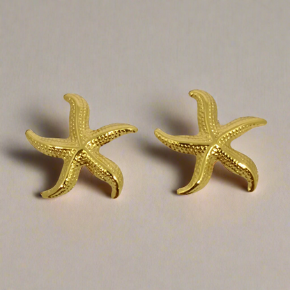 Gold starfish earrings on a light gray background