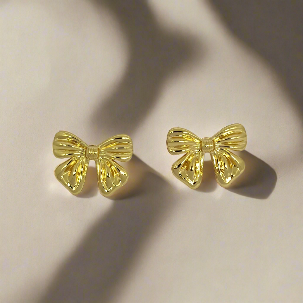 Gold bow-shaped earrings on a light background