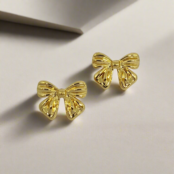 Gold bow-shaped earrings on a light gray background