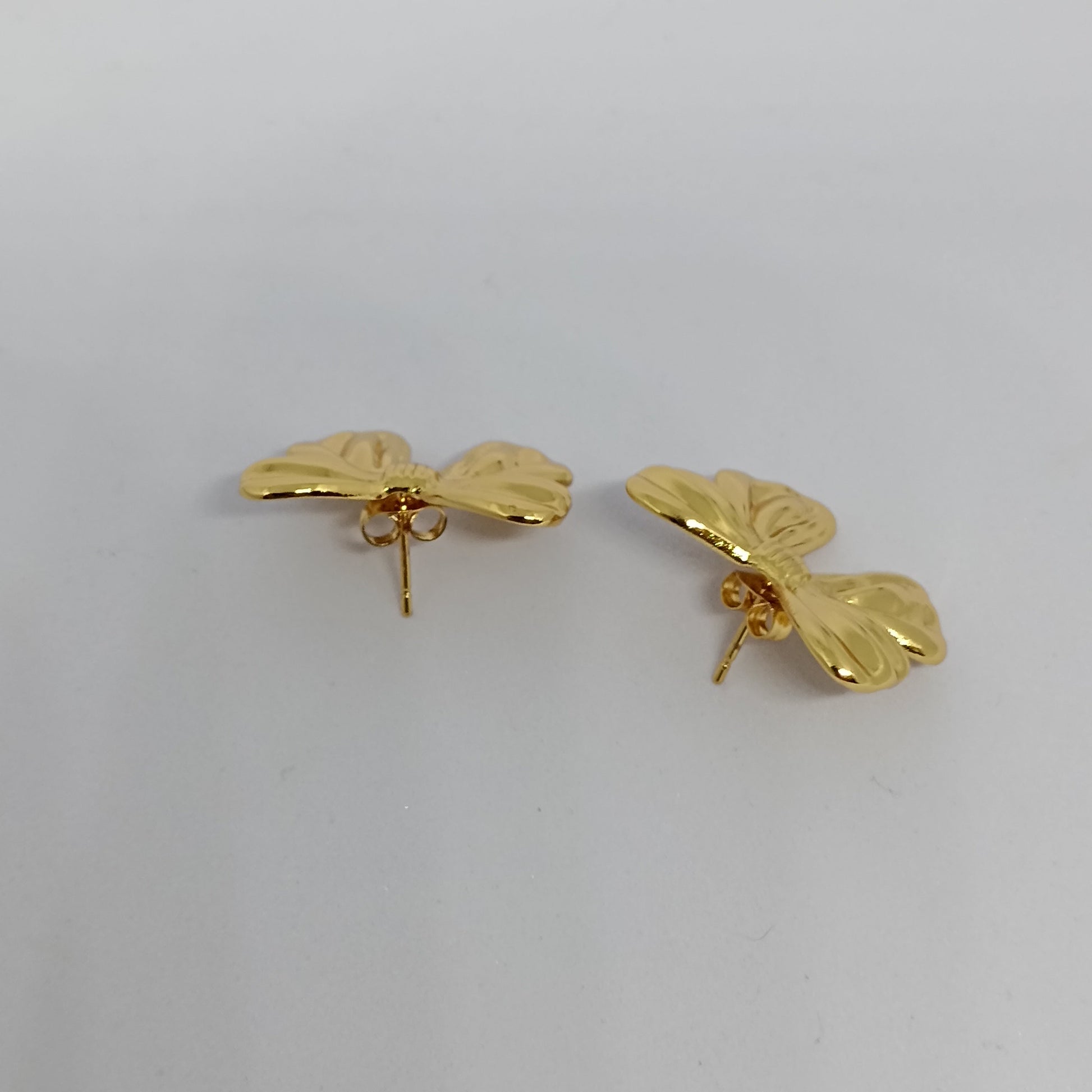 Pair of gold butterfly-shaped earrings on a light gray background