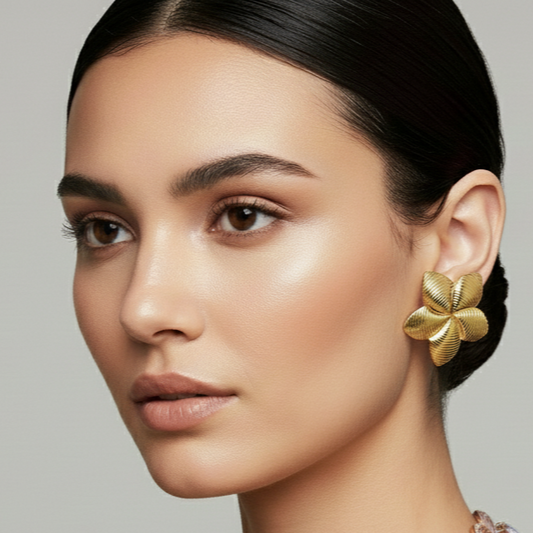 Close-up of a woman wearing gold floral earrings against a neutral background