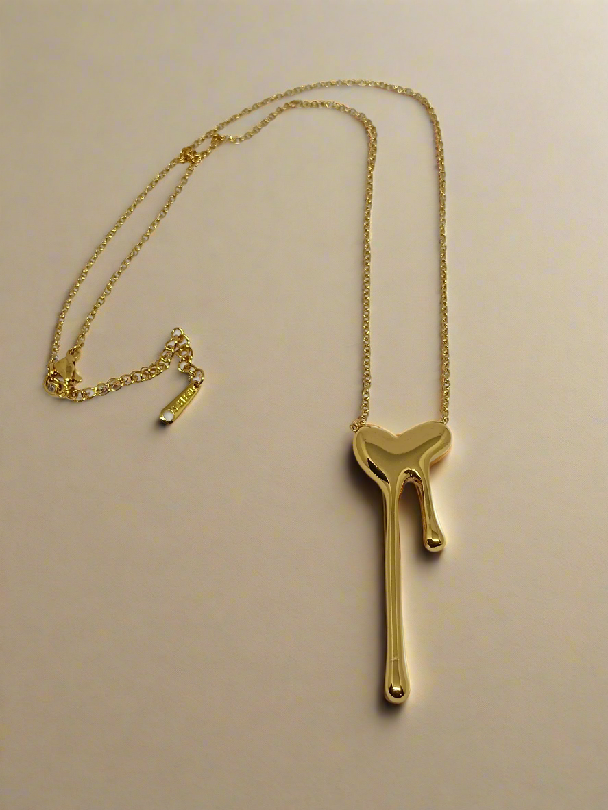Gold necklace with a unique pendant on a light gray background