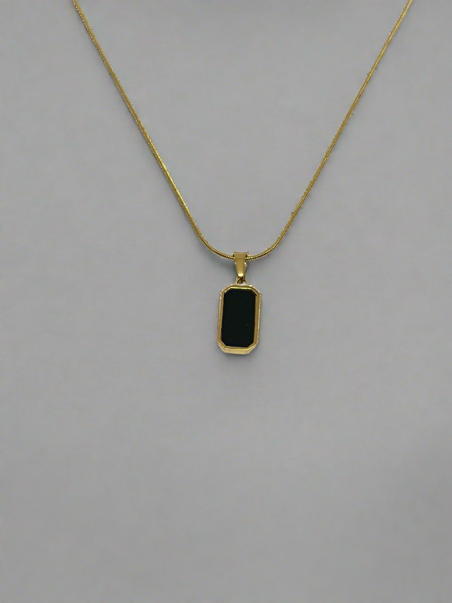 Gold necklace with a black pendant on a white background