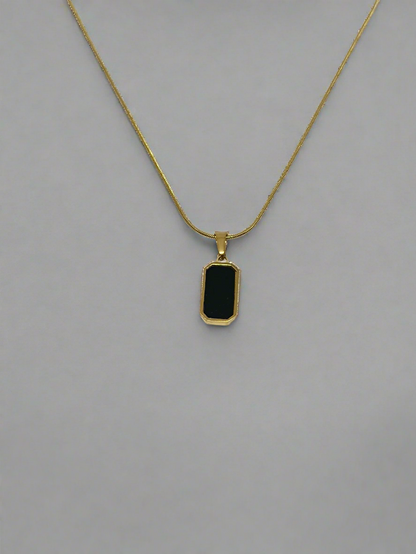 Gold necklace with a black pendant on a white background