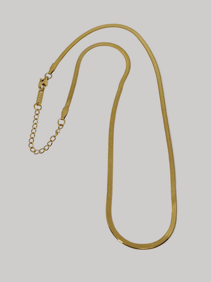 Gold chain necklace on a light gray background