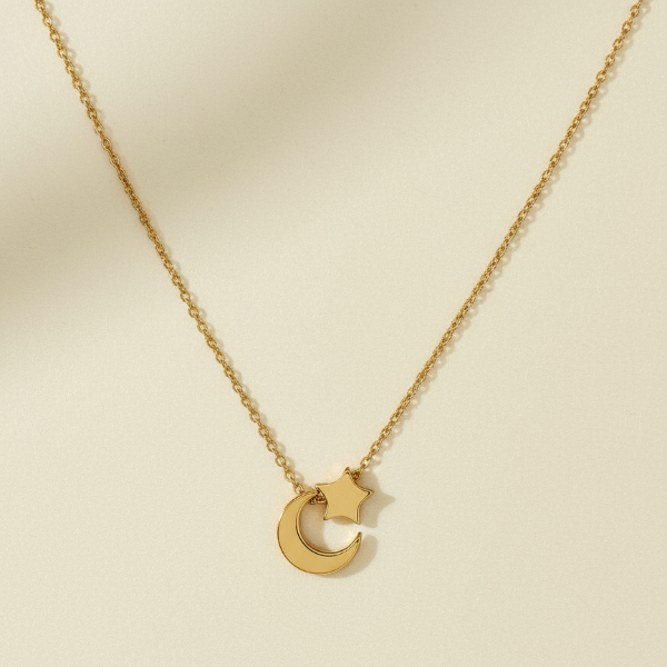 Gold necklace with a crescent moon pendant on a beige background