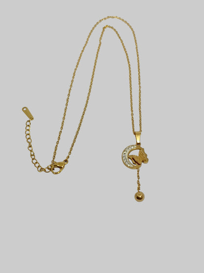 Gold necklace with a small pendant on a light gray background
