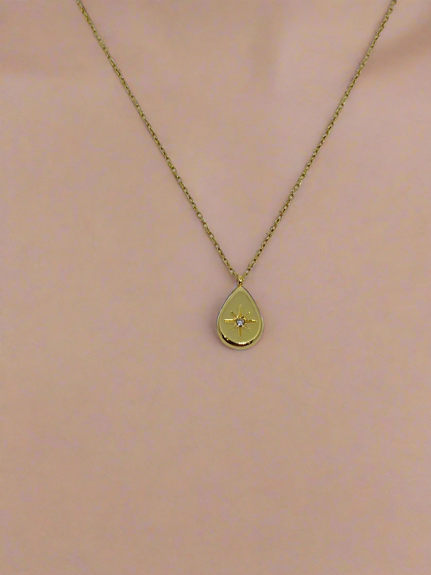 Gold necklace with a teardrop-shaped pendant on a white background