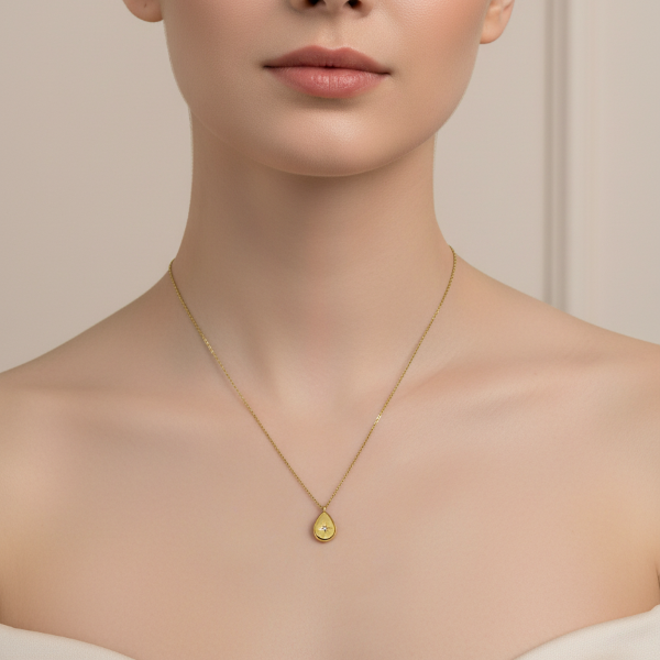 Golden necklace with a pendant worn by a model against a neutral background