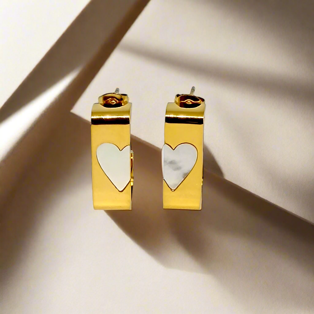 Gold hoop earrings with heart-shaped charms on a white background