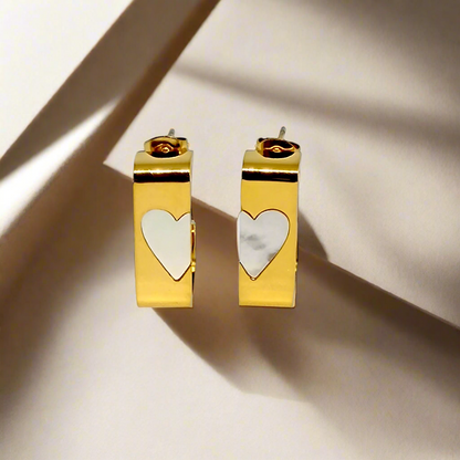 Gold hoop earrings with heart-shaped charms on a white background