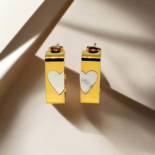 Gold hoop earrings with heart-shaped charms on a white background