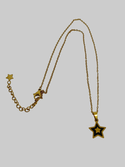 Gold necklace with star pendant on a light gray background