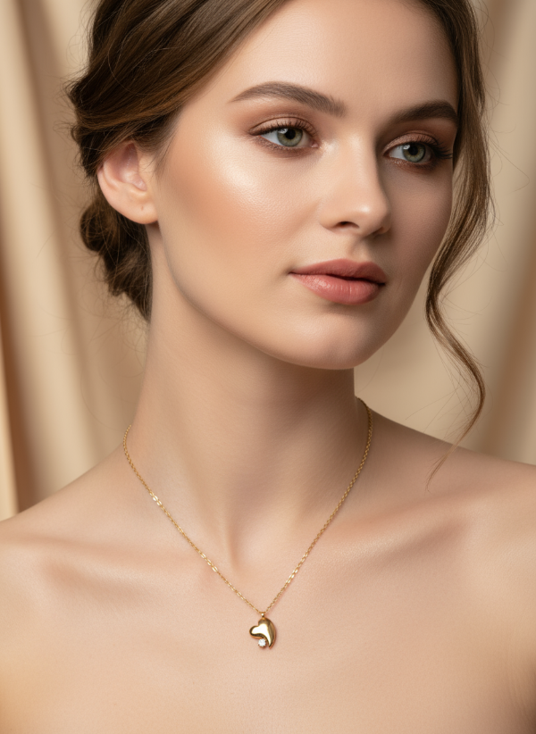Woman wearing a gold necklace with a heart pendant against a beige background