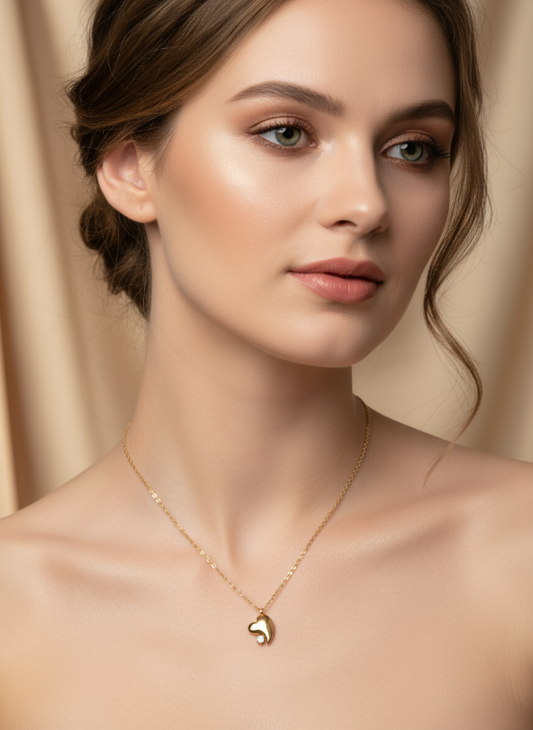 Woman wearing a gold necklace with a heart pendant against a beige background