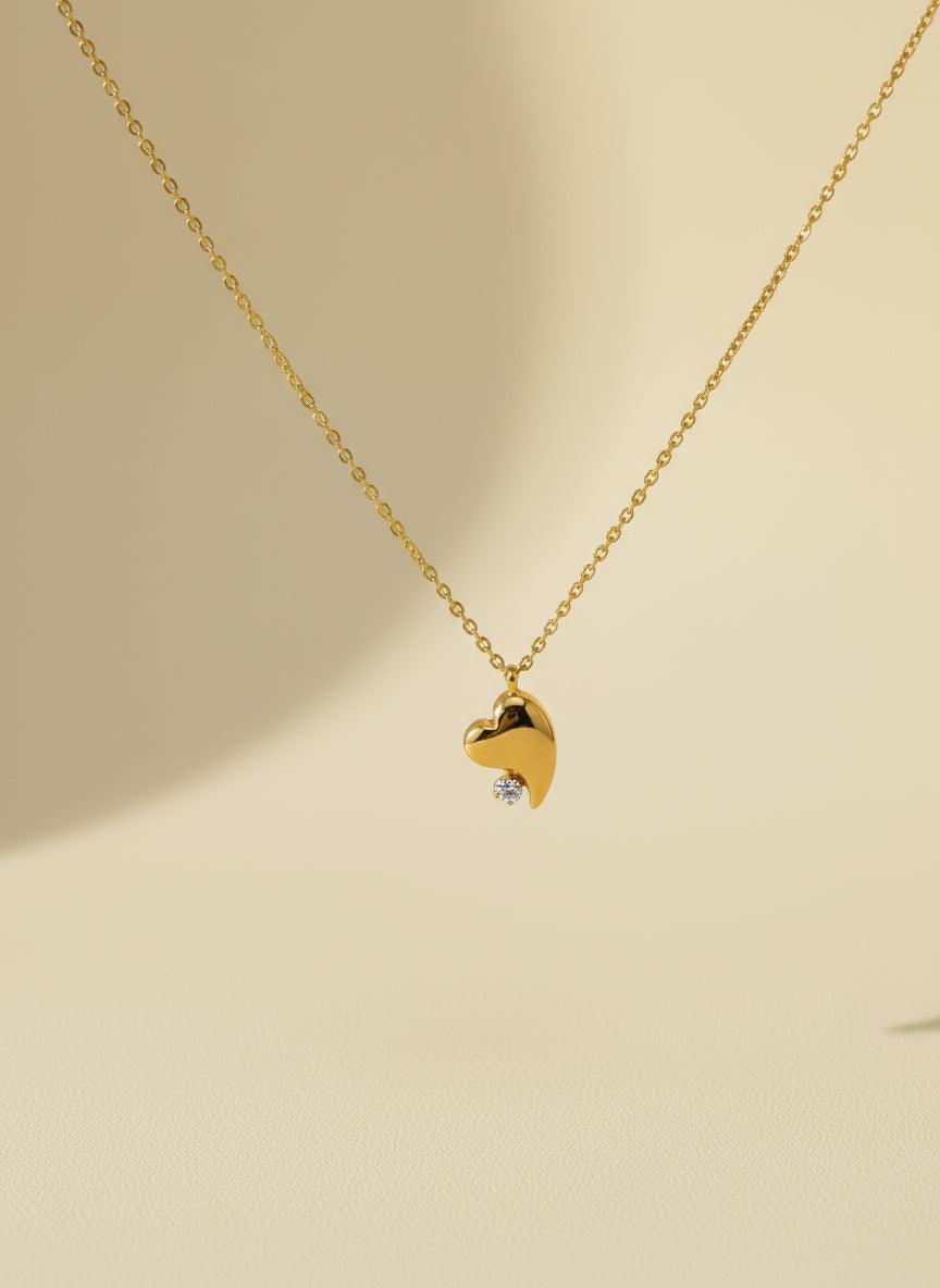 Gold heart-shaped necklace with a diamond on a white card