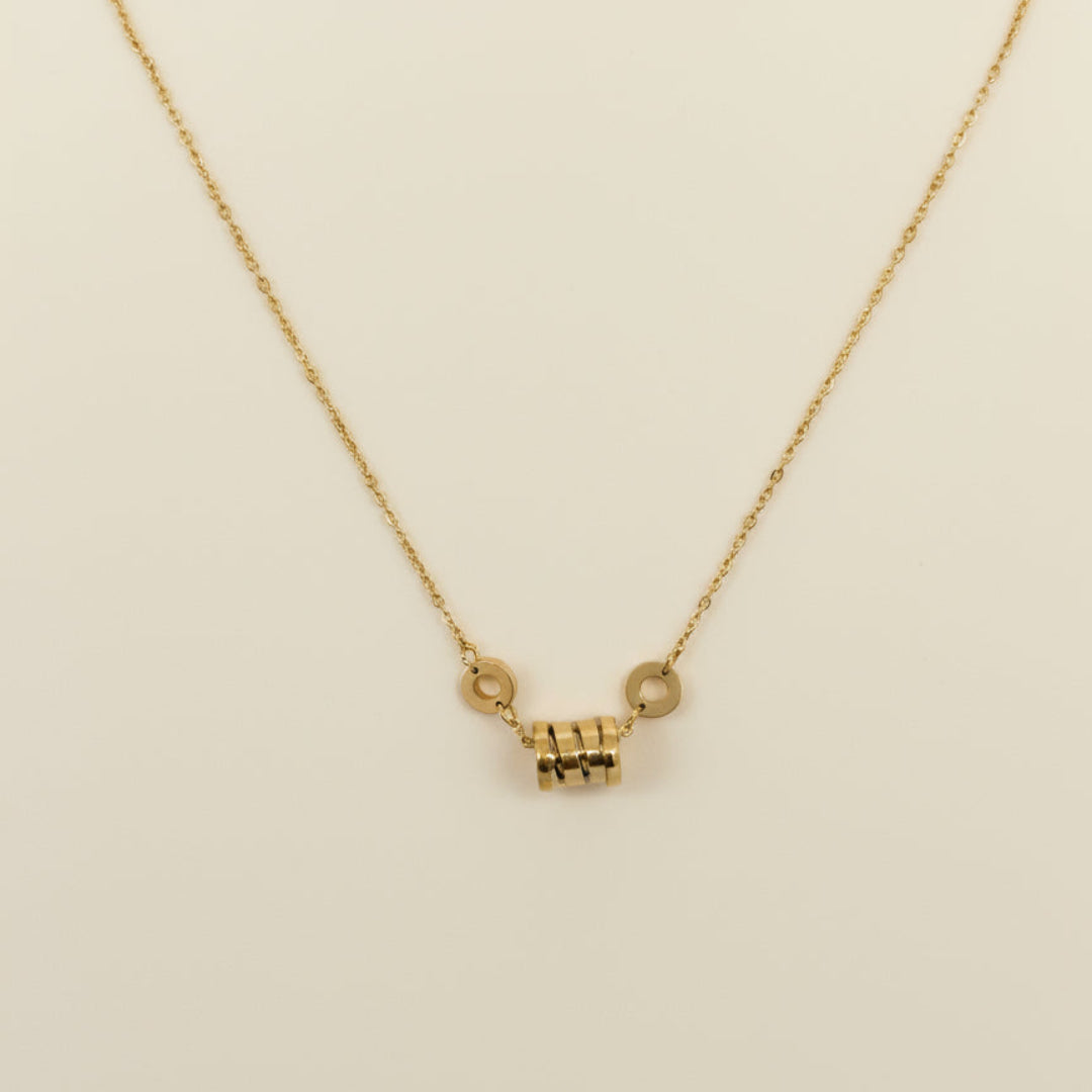 Gold necklace with a small pendant on a white background