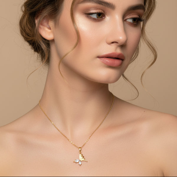 Woman wearing a golden necklace with a butterfly pendant against a beige background