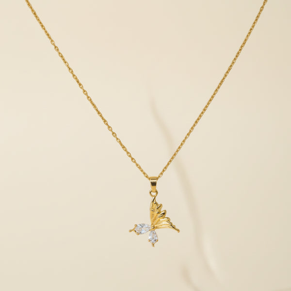 Golden necklace with a butterfly pendant on a plain background