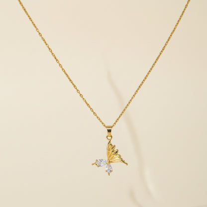 Golden necklace with a butterfly pendant on a plain background