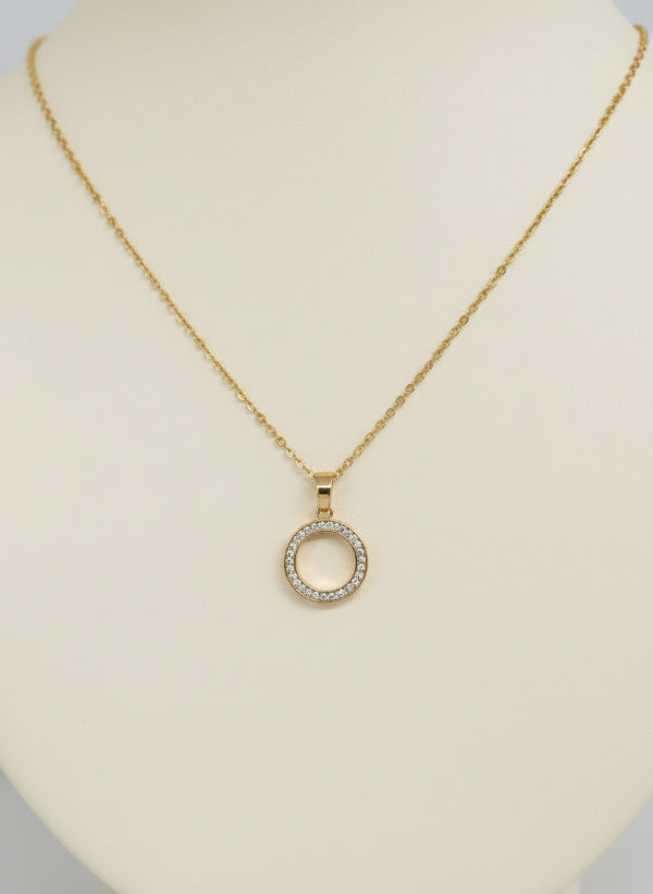 Gold necklace with a circular pendant on a gray card