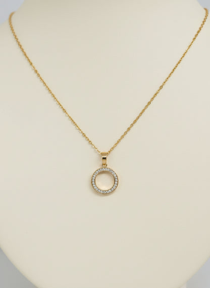 Gold necklace with a circular pendant on a gray card