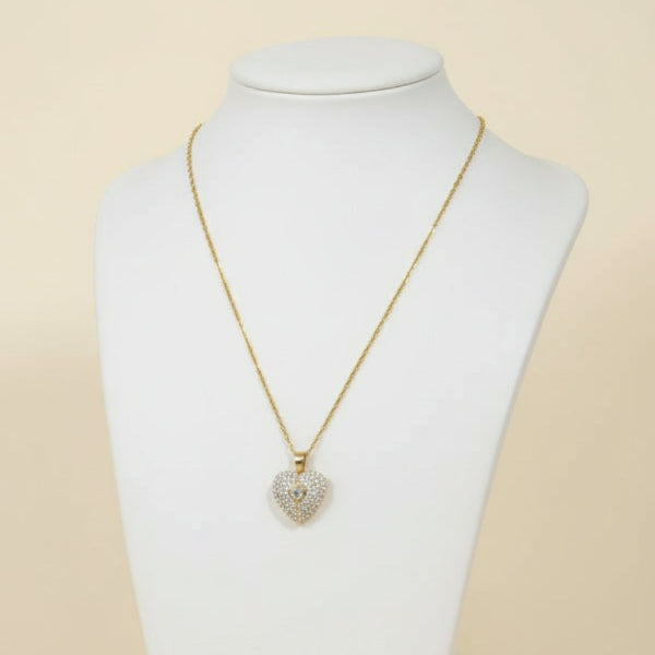 Heart-shaped diamond pendant on a gold chain against a white background