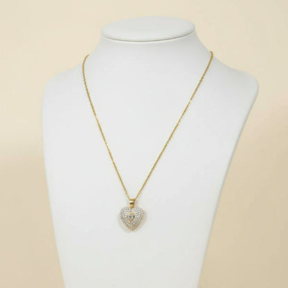 Heart-shaped diamond pendant on a gold chain against a white background