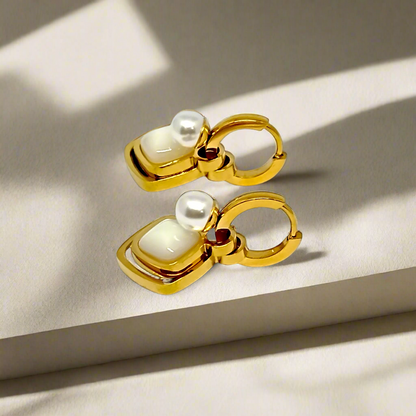 Gold earrings with pearl-like stones on a white background