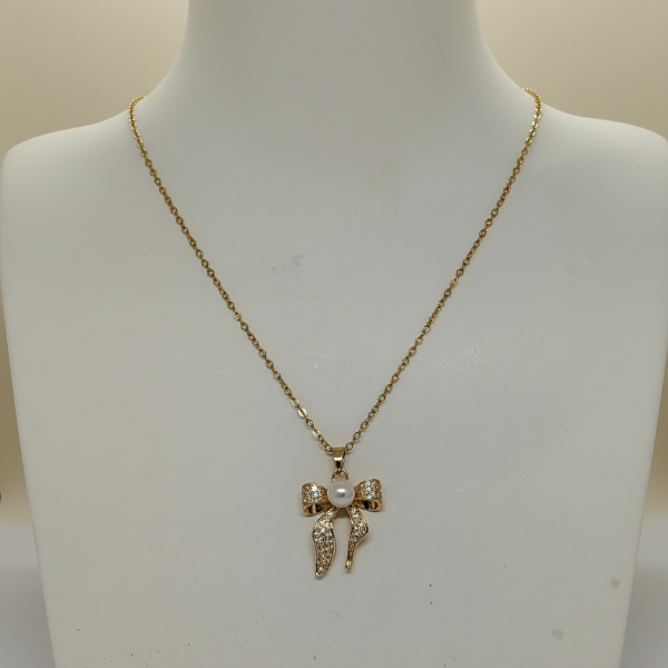 Gold necklace with a bow pendant on a mannequin bust.