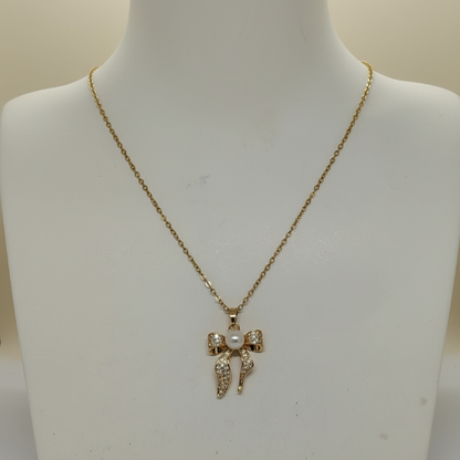 Gold necklace with a bow pendant on a mannequin bust.