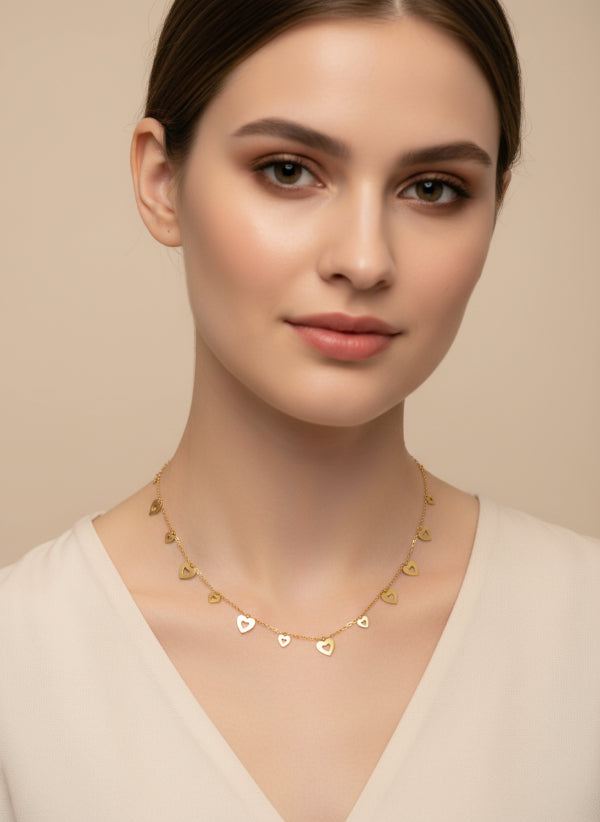 Woman wearing a golden necklace with heart-shaped pendants on a beige background