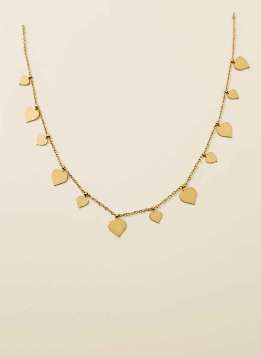 Gold necklace with heart-shaped pendants on a beige background