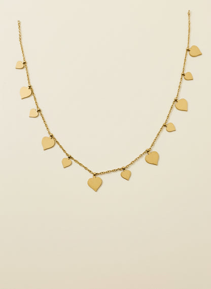 Gold necklace with heart-shaped pendants on a beige background