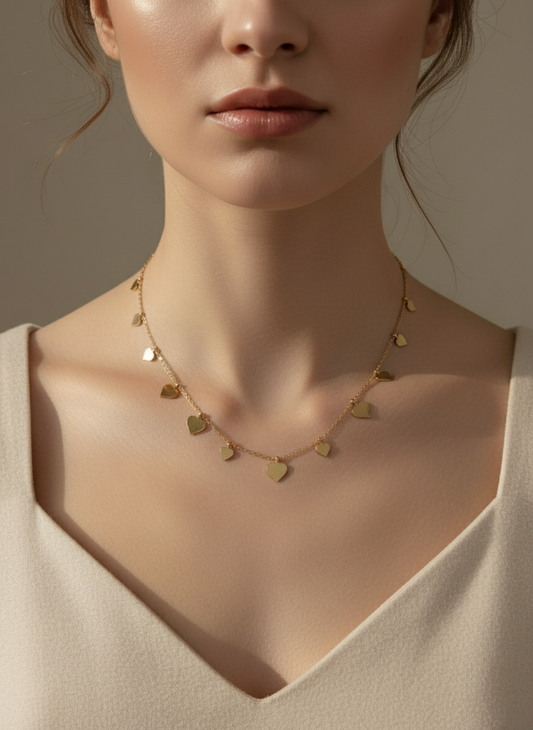 Woman wearing a gold heart-shaped necklace against a neutral background