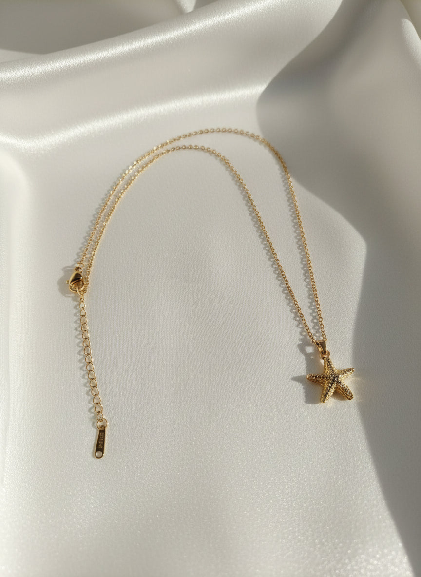 Golden necklace with a star pendant on a white surface