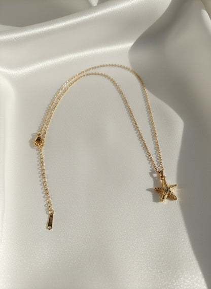 Golden necklace with a star pendant on a white surface
