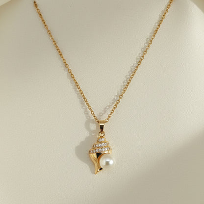 Gold necklace with a shell and pearl pendant on a gray card