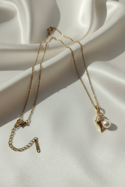 Gold necklace with a pearl pendant on a white fabric background