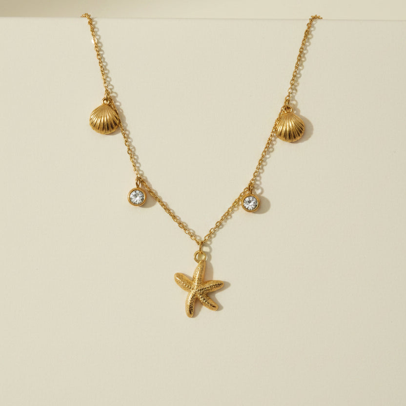 Golden necklace with a starfish pendant on a gray card