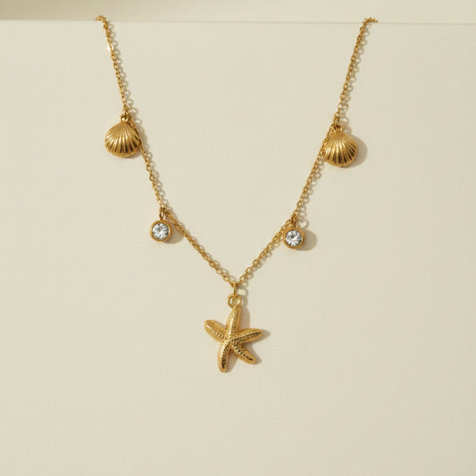 Golden necklace with a starfish pendant on a gray card