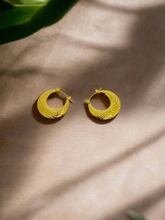 Gold hoop earrings on a pink background