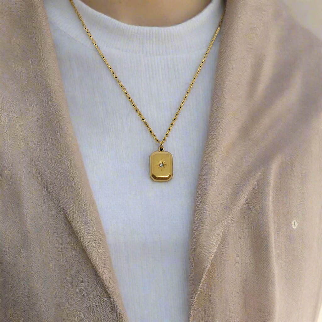 Gold necklace with a square pendant on a white background